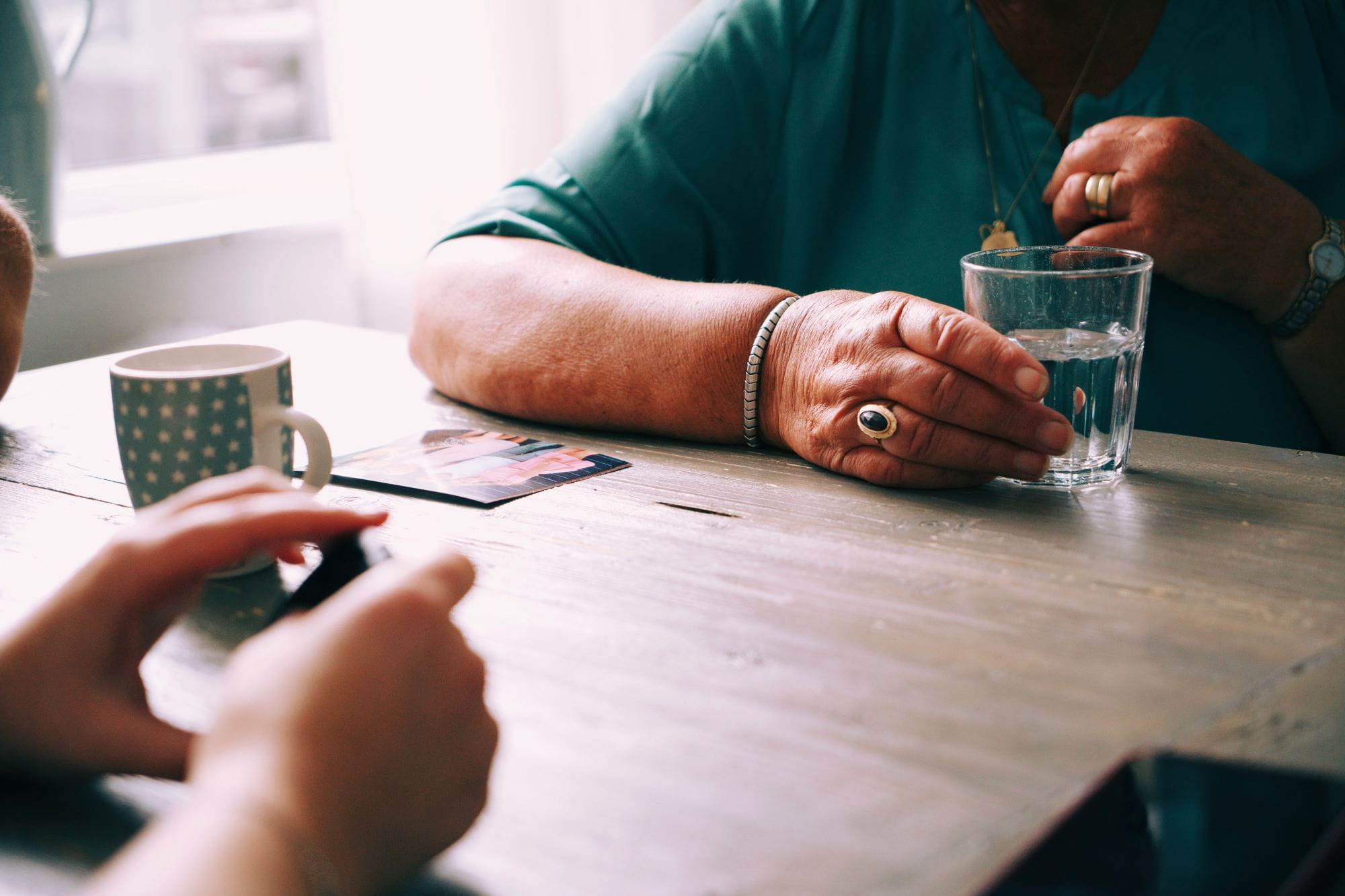Two women sitting at a table across form each other, one with a glass of clear water