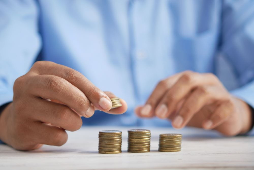 A close-up of hands stacking quarters into 3 neat rows