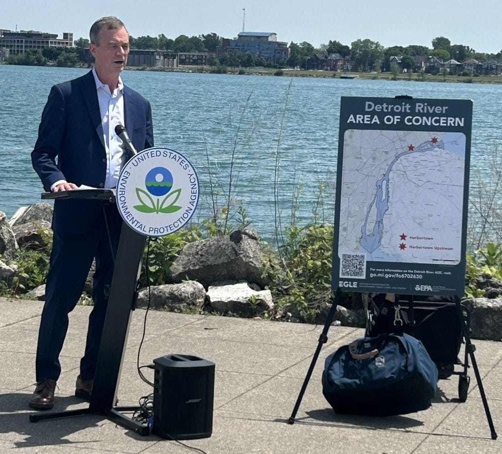 EGLE Director Phil Roos standing next to poster on easel at Detroit River Area of Concern event.
