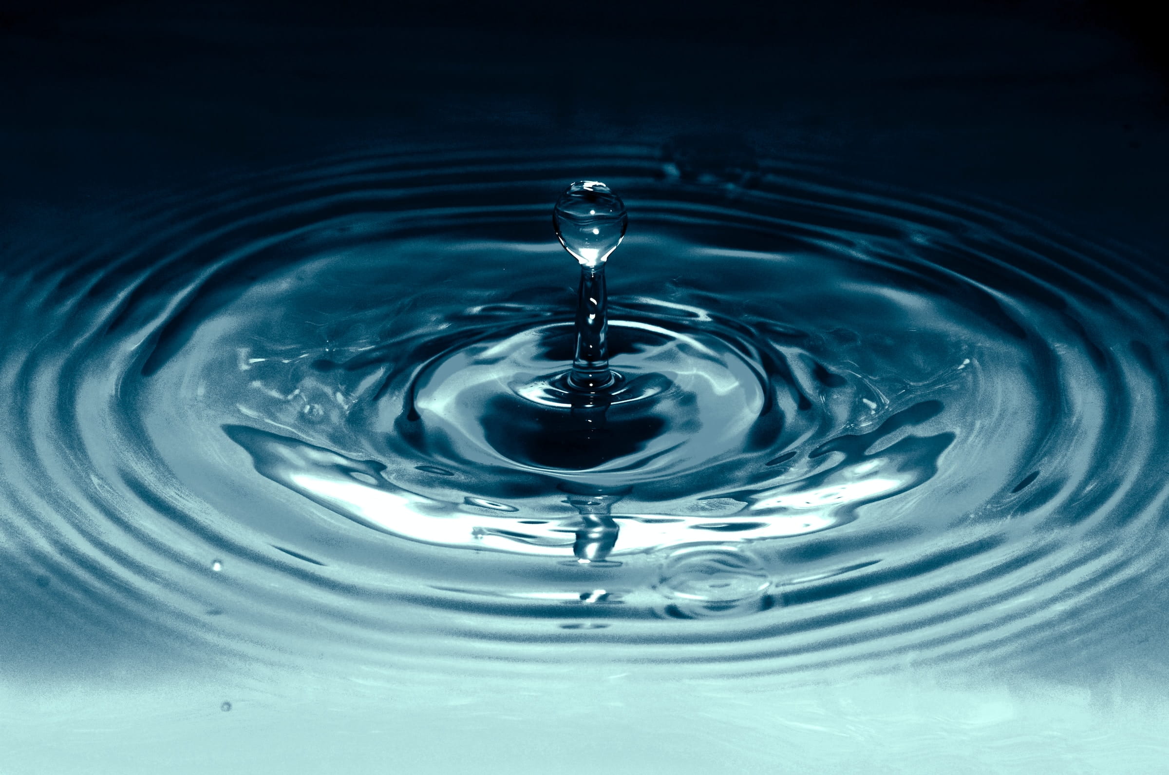 A single drop of water making a small splash and small ripples
