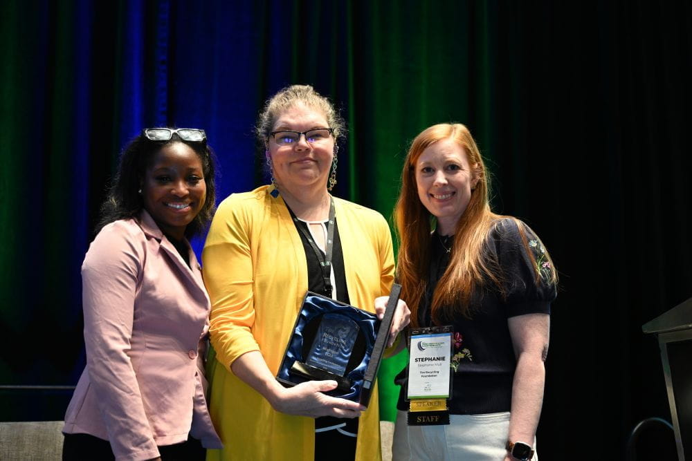 Kirsten Clemens, EGLE’s scrap tire coordinator (center), receives an award from the Tire Recycling Foundation for the department’s scrap tire market development efforts. 