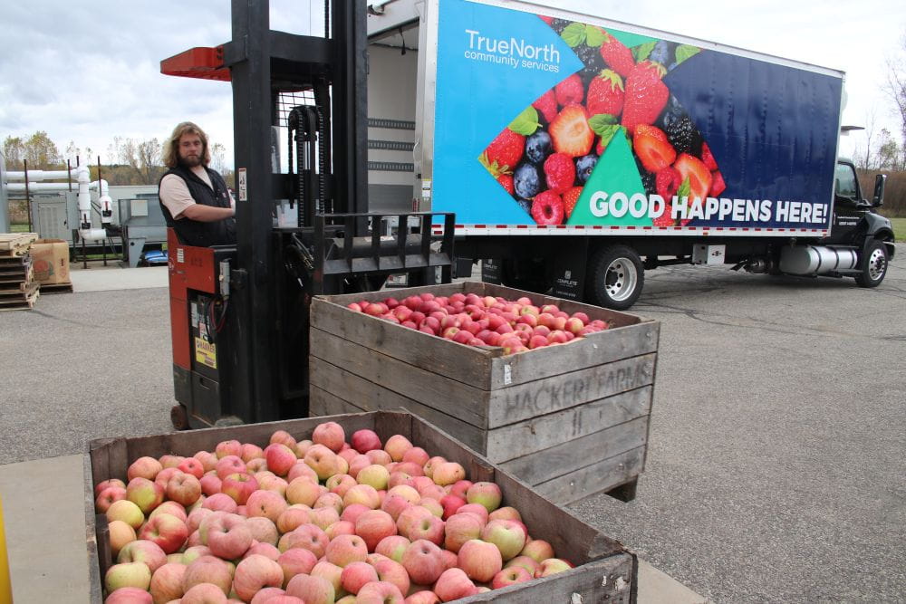 Worker at TrueNorth Community Services loading rescued apples into a refrigerated box truck.