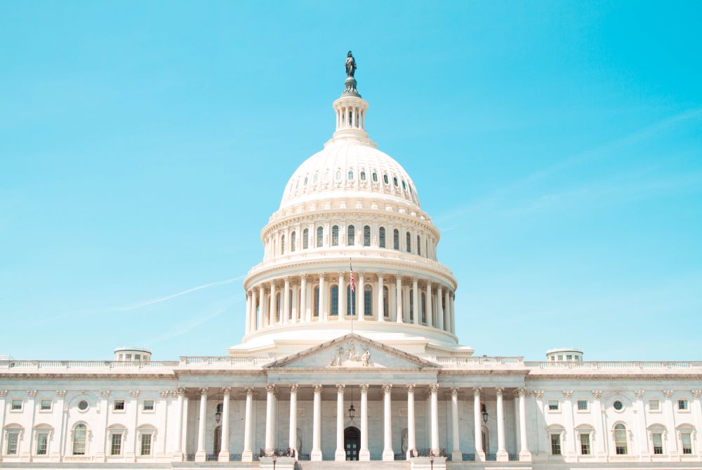The front of the United States capitol building; the stark white building contrasts pleasantly with the powder blue sky
