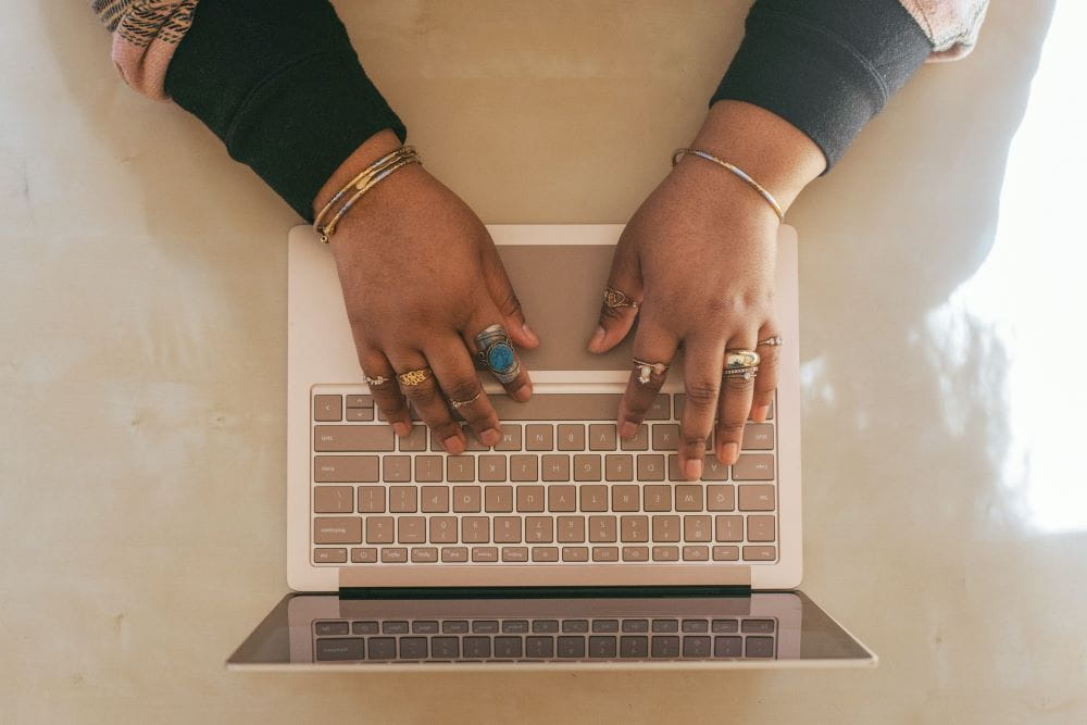 An overhead view of a woman typing on a laptop