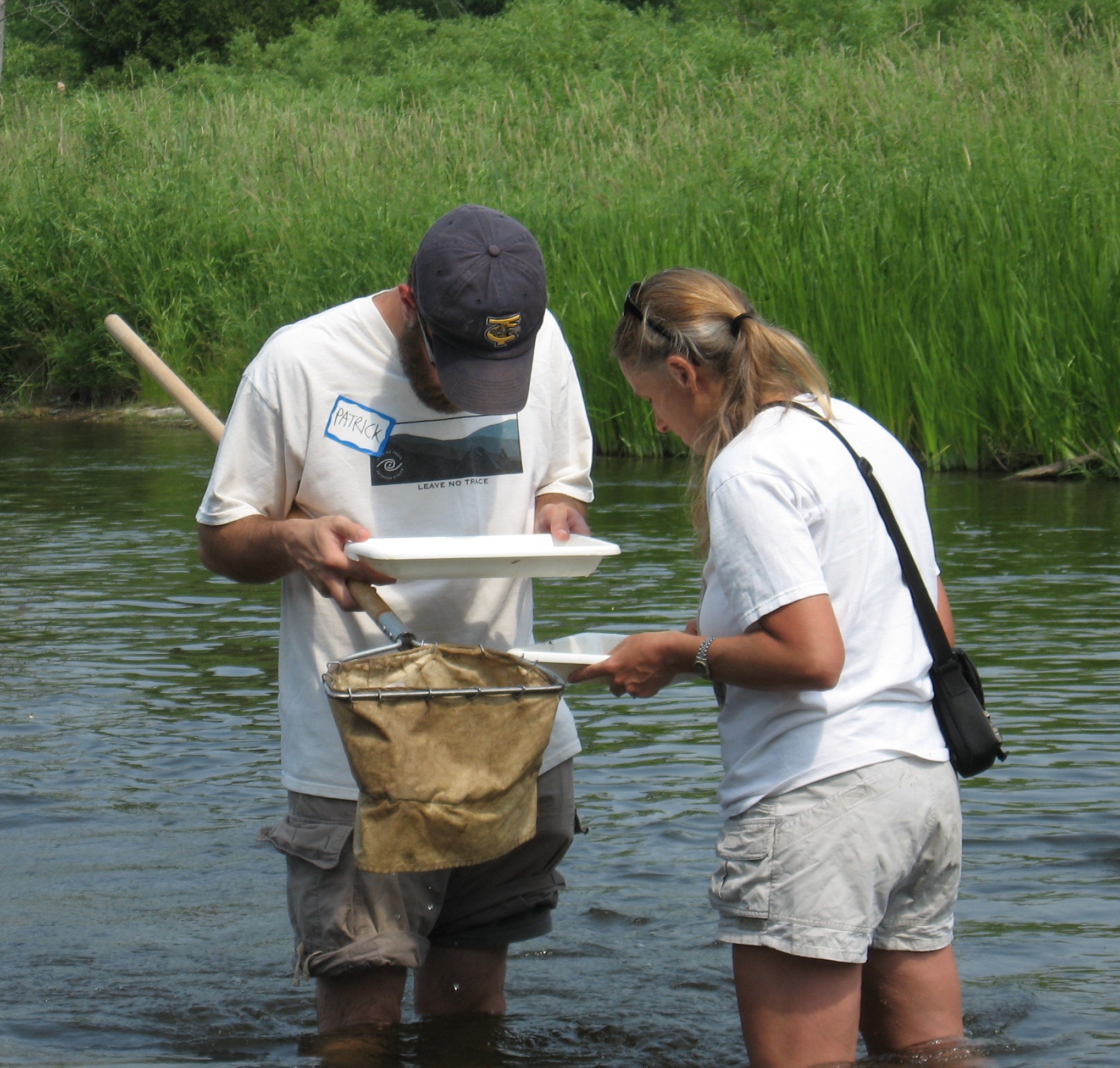Two MiCorps volunteers standing knee-deep in the Chippewa River looking at a net