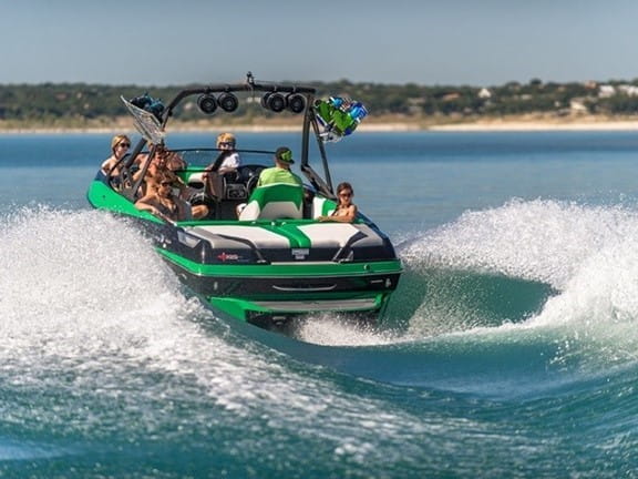 A family on a green boat cruising across an inland lake on a summer day