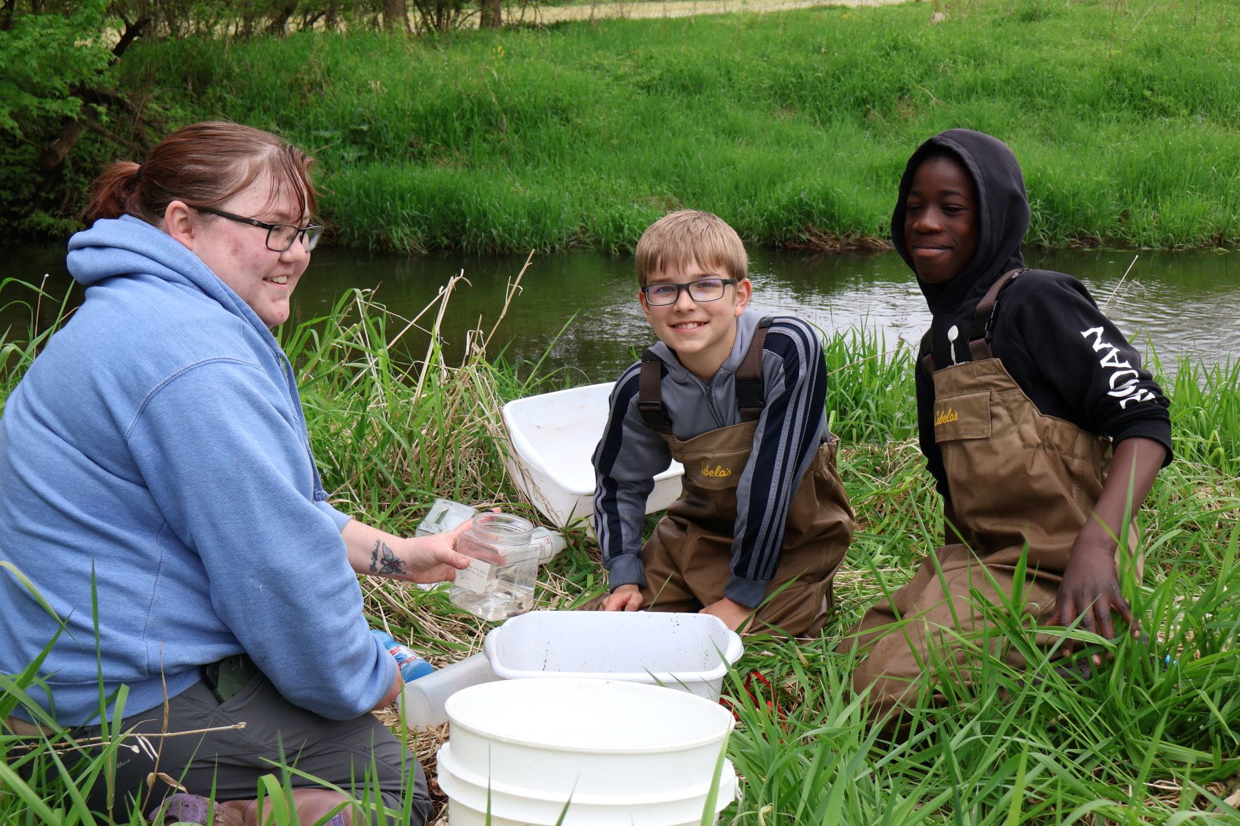 Three volunteers pick through bugs at a stream monitoring site in 2024.