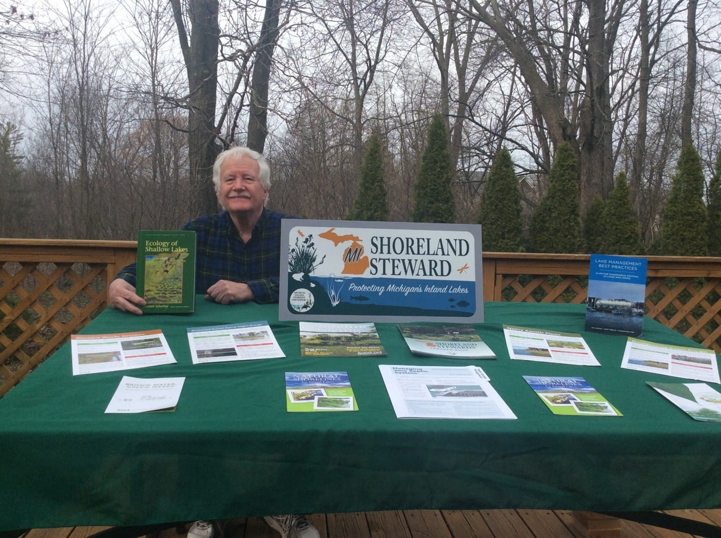 Bob Ripstra sitting at a table with Hess Lake and Shoreland Stewards information.