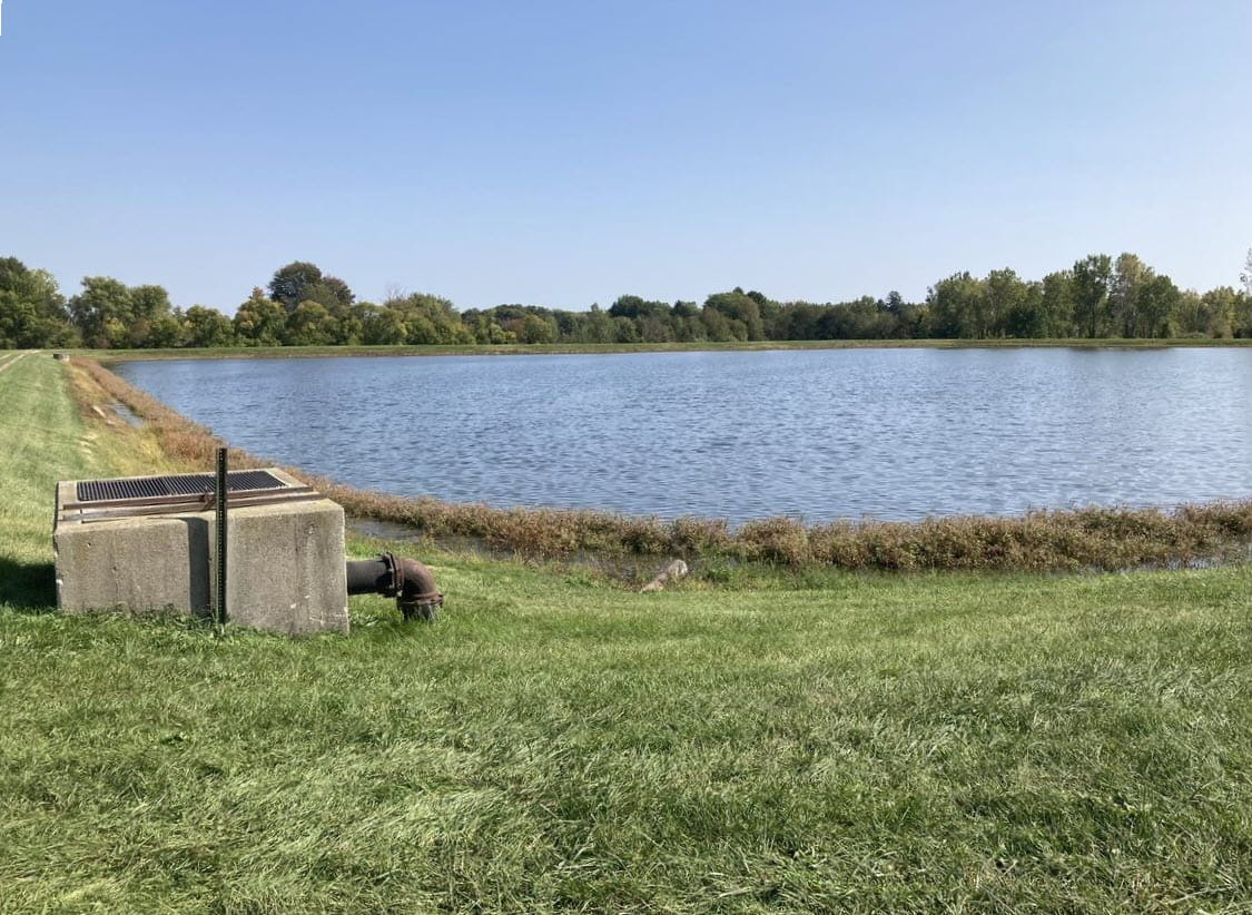 A small pipe at the shoreline of a shallow drainage basin