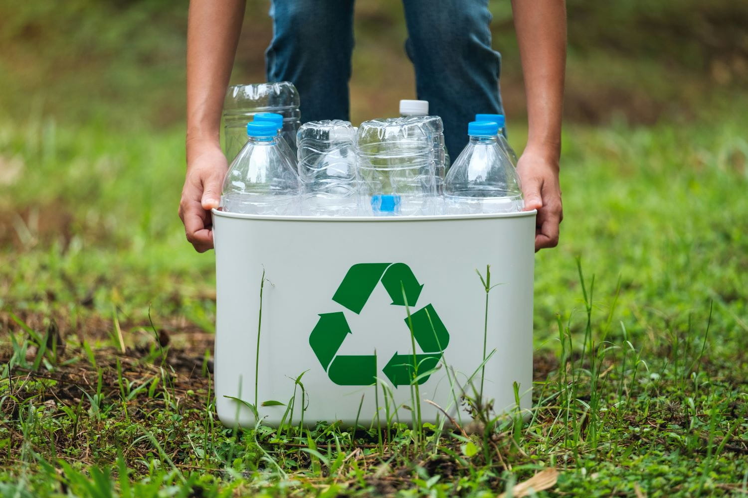 A metal recycling bin holding clear plastic water bottles