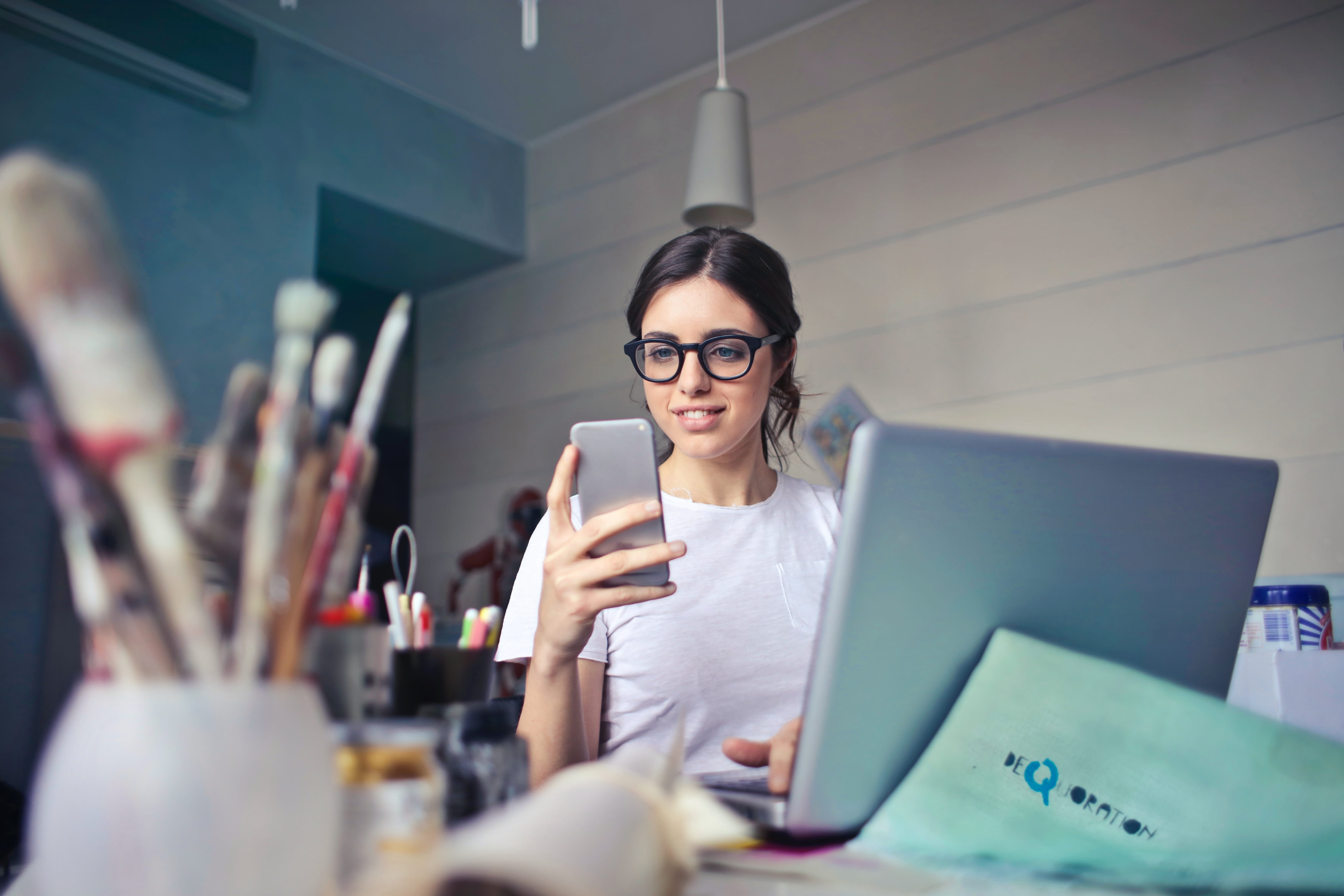 Photo of  a woman sitting at her desk looking at her phone.