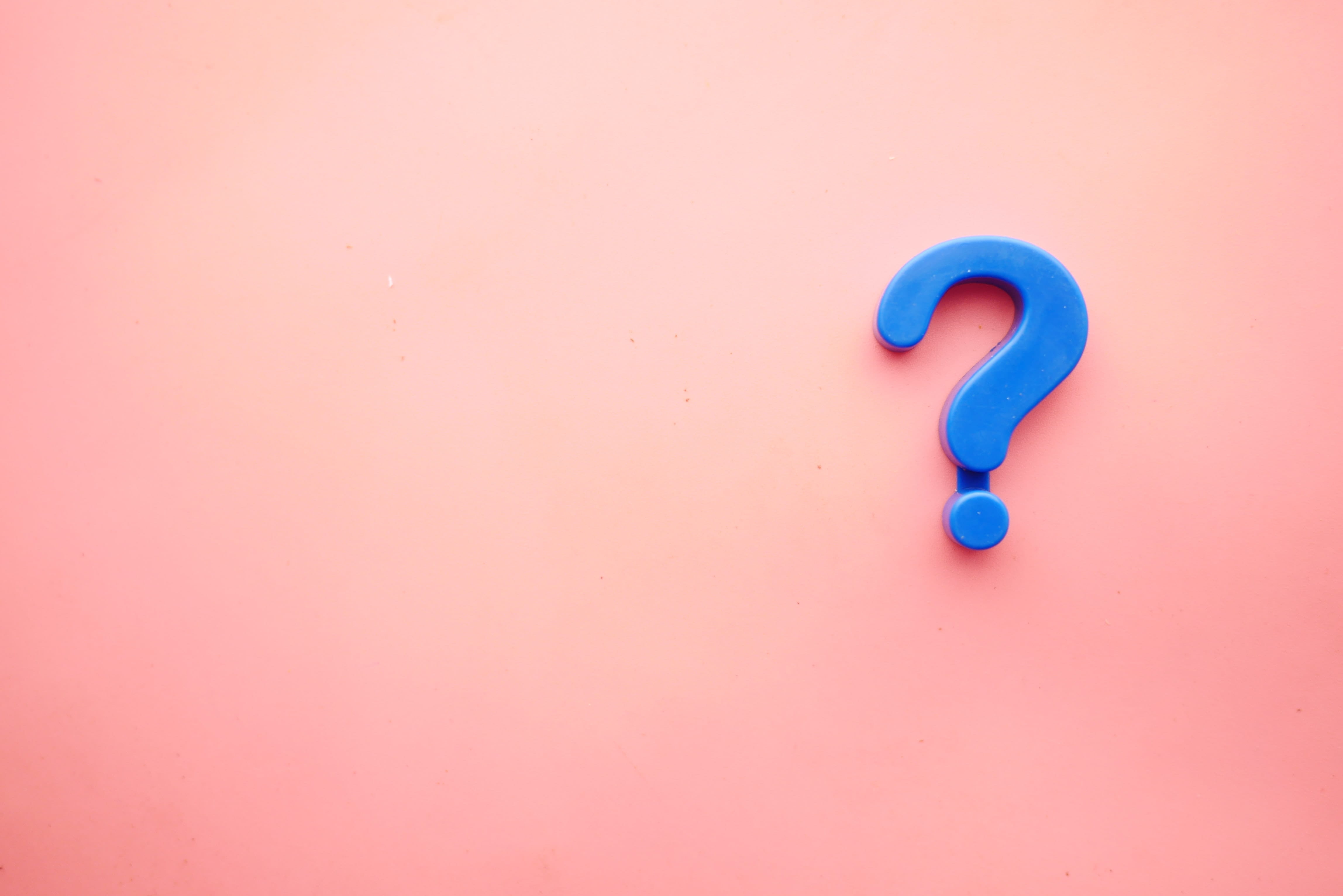 Photo of a question mark on a pink background.