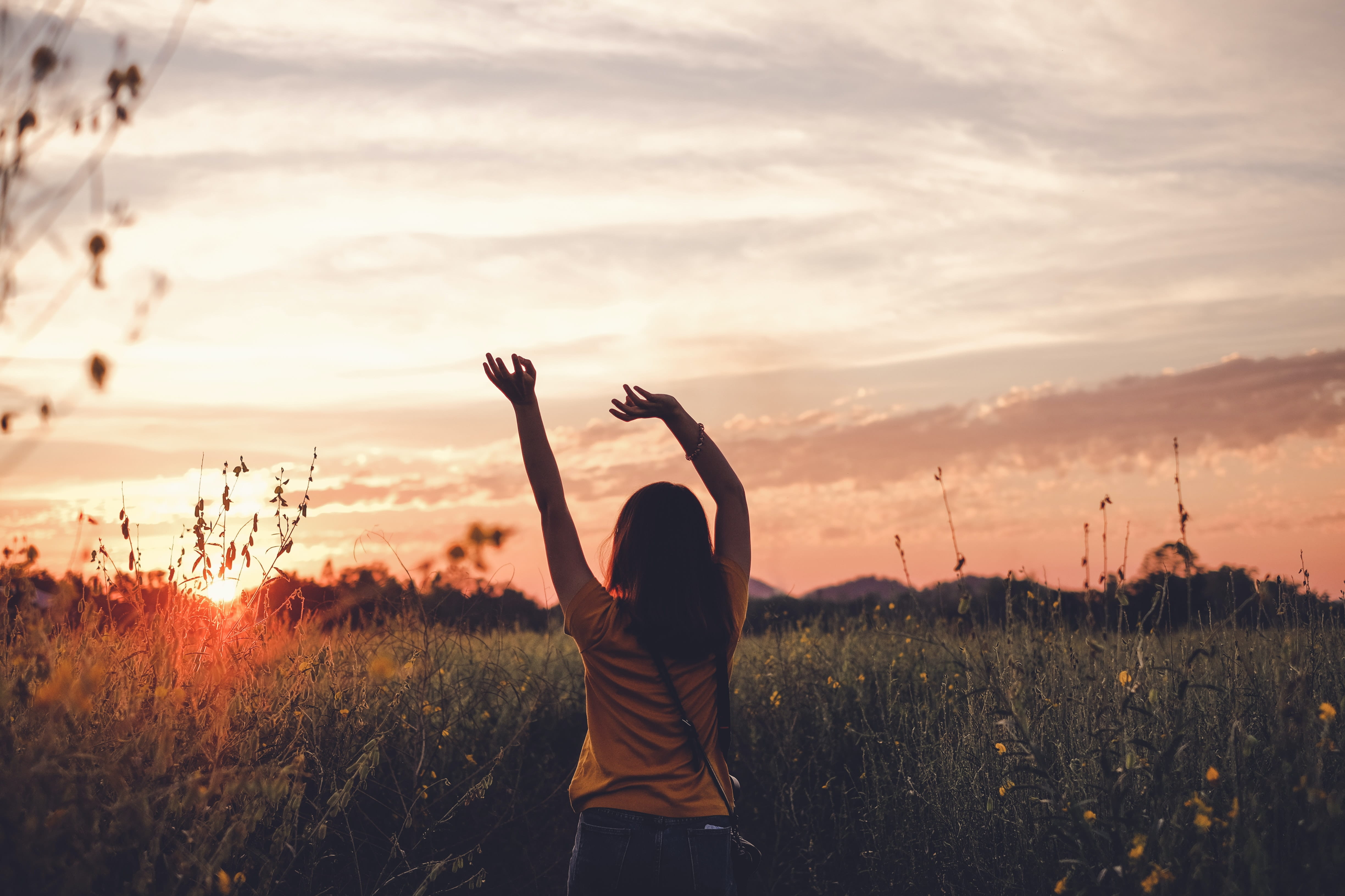 Photo of a woman in a field at sunrise.