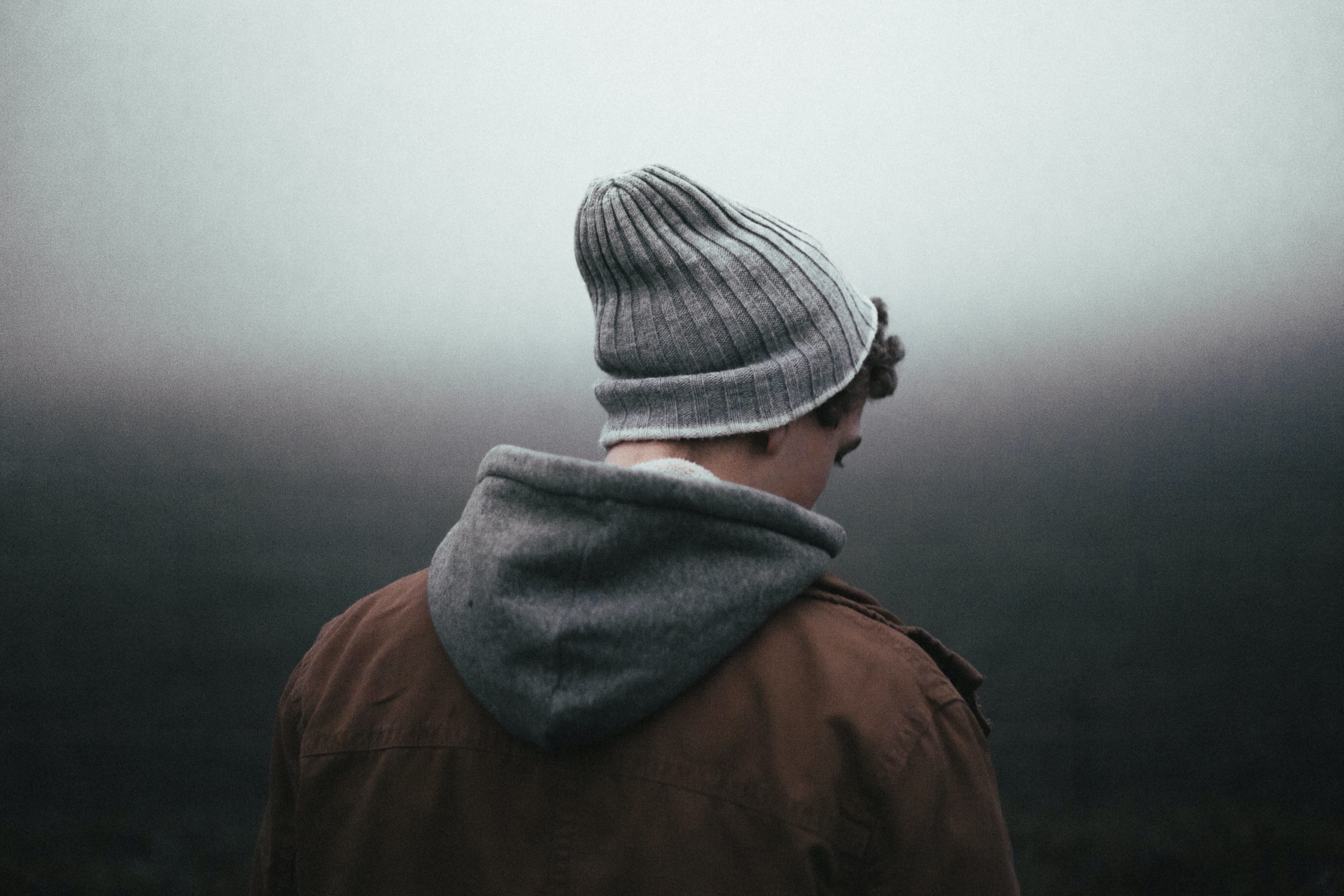 Photo of a younger man in beanie looking downwards.