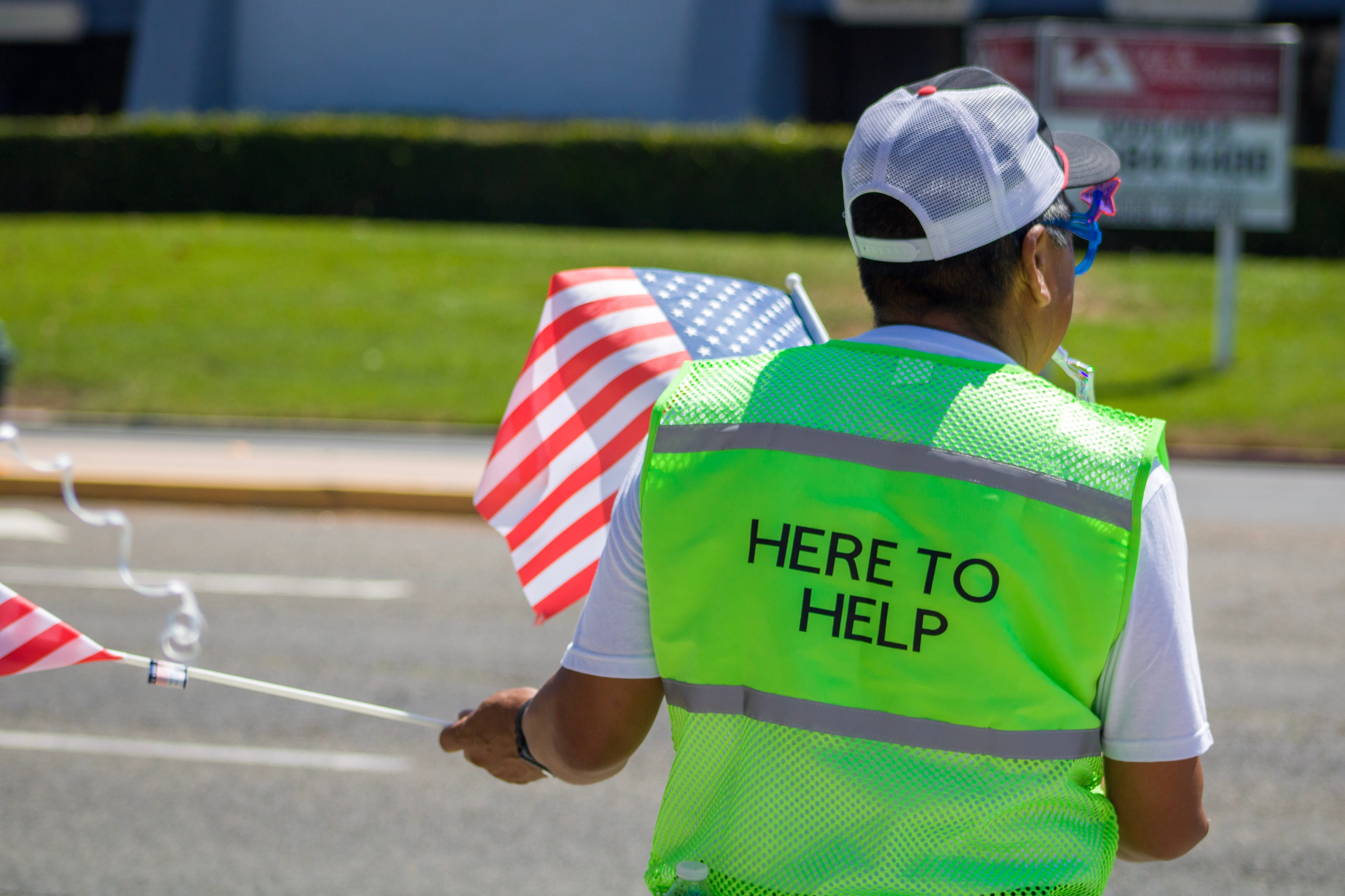 Photo of a person in a green vest that says "Here to Help".