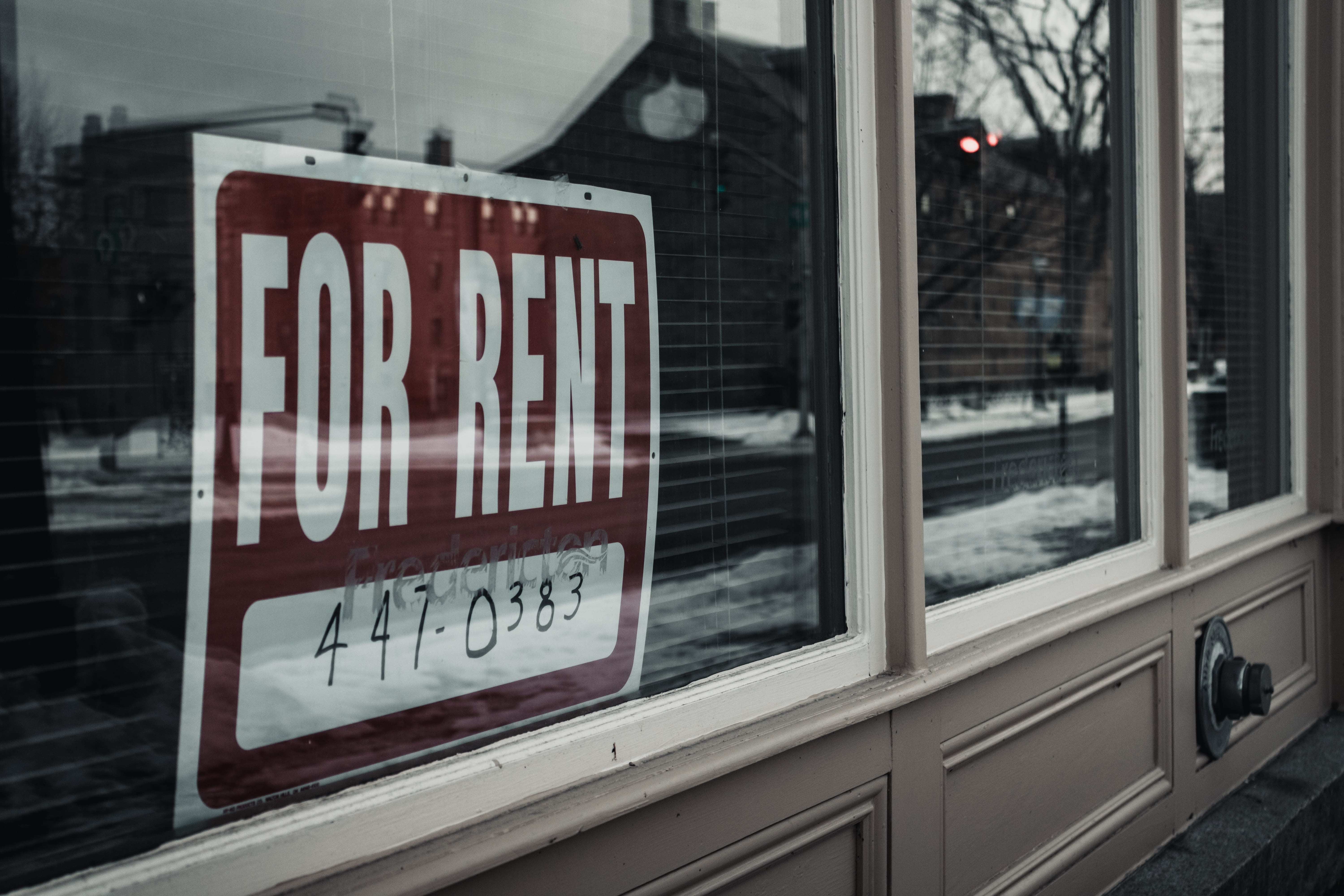 Photo of a 'For Rent' sign in a window.