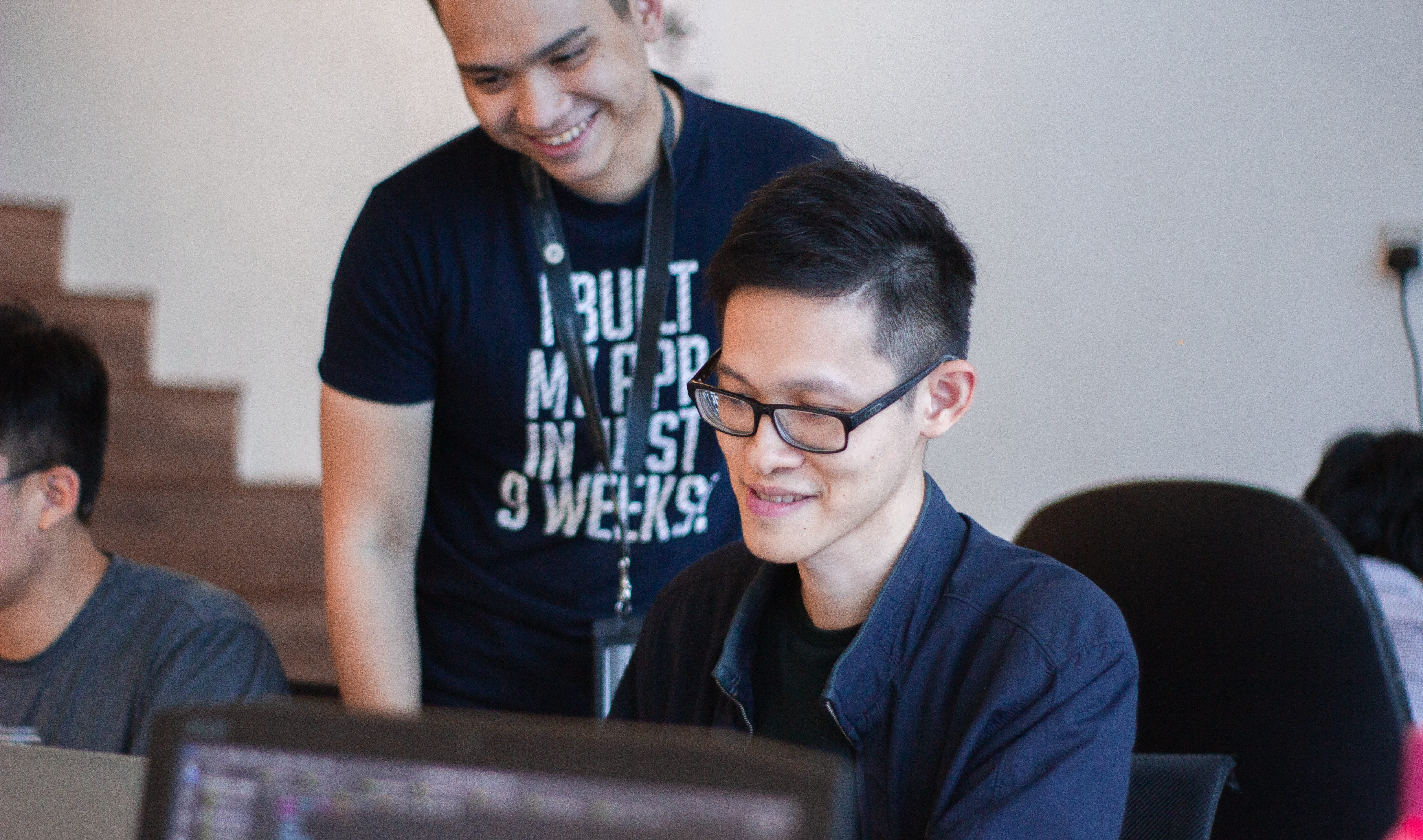 Photo of a person mentoring another in a computer lab.