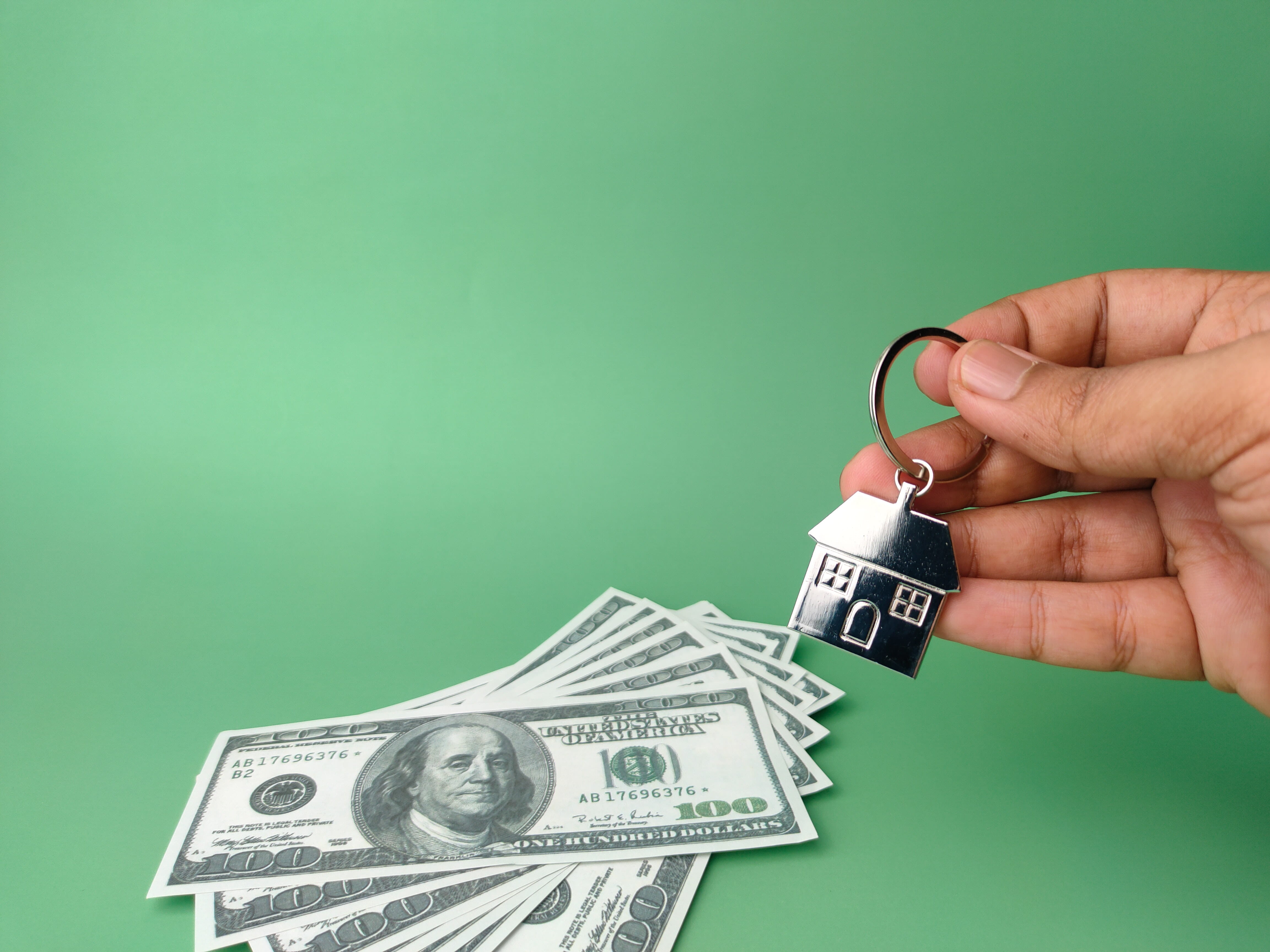 Photo of money next to a house shaped keychain.