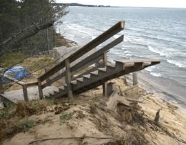 photograph of stairs leading from beach to nowhere as erosion has destroyed the deck at residence