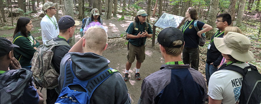 Group of students standing in the woods with DNR park interpreter talking to them