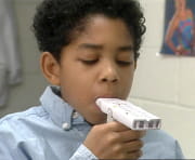 boy using peak flow meter to measure inhalations
