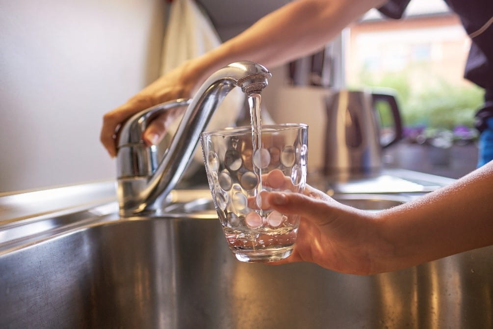 Glass of water being filled under kitchen faucet