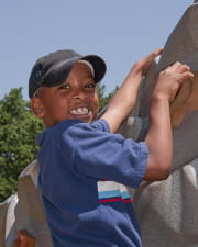smiling boy ascending rock climbing wall on playground