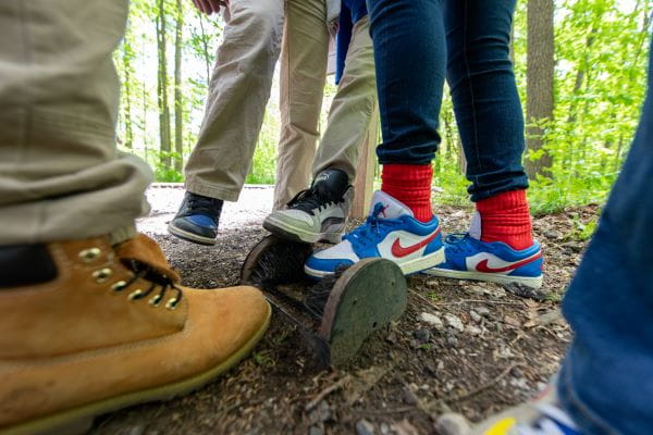 Children using a boot brush to remove debris and dirt from their shoes and boots.