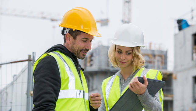 2 Individuals in a construction setting looking at plans