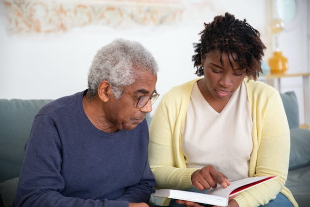 Two Individuals Reading a Book at a Home for the Aged