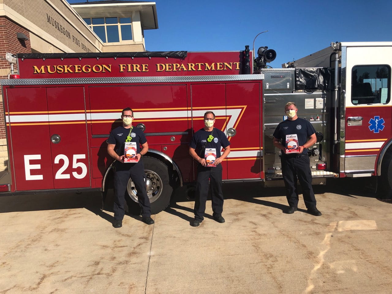 firefighters posing with smoke alarms in front of fire truck