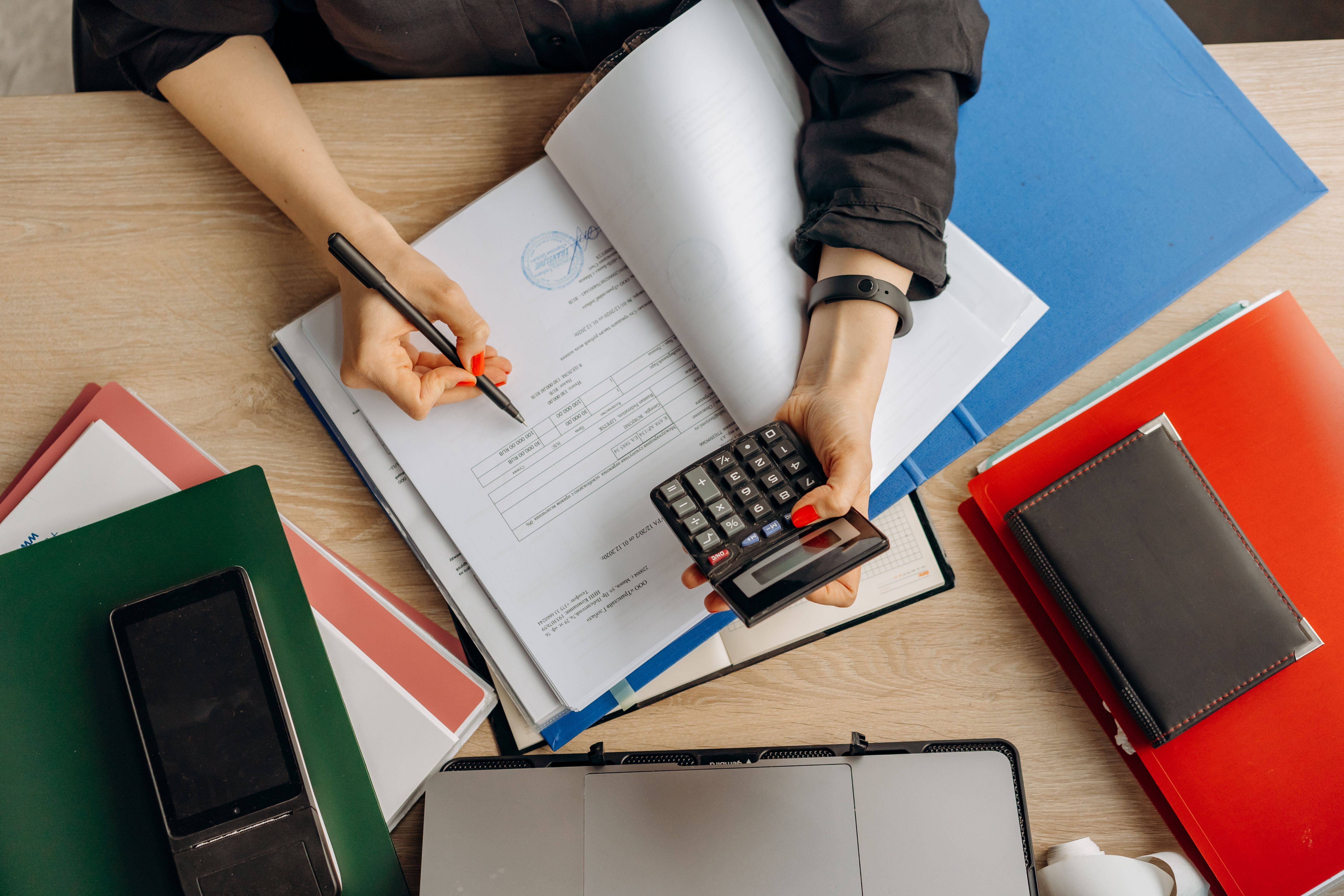 Accountant holding pen and calculator while reviewing documents