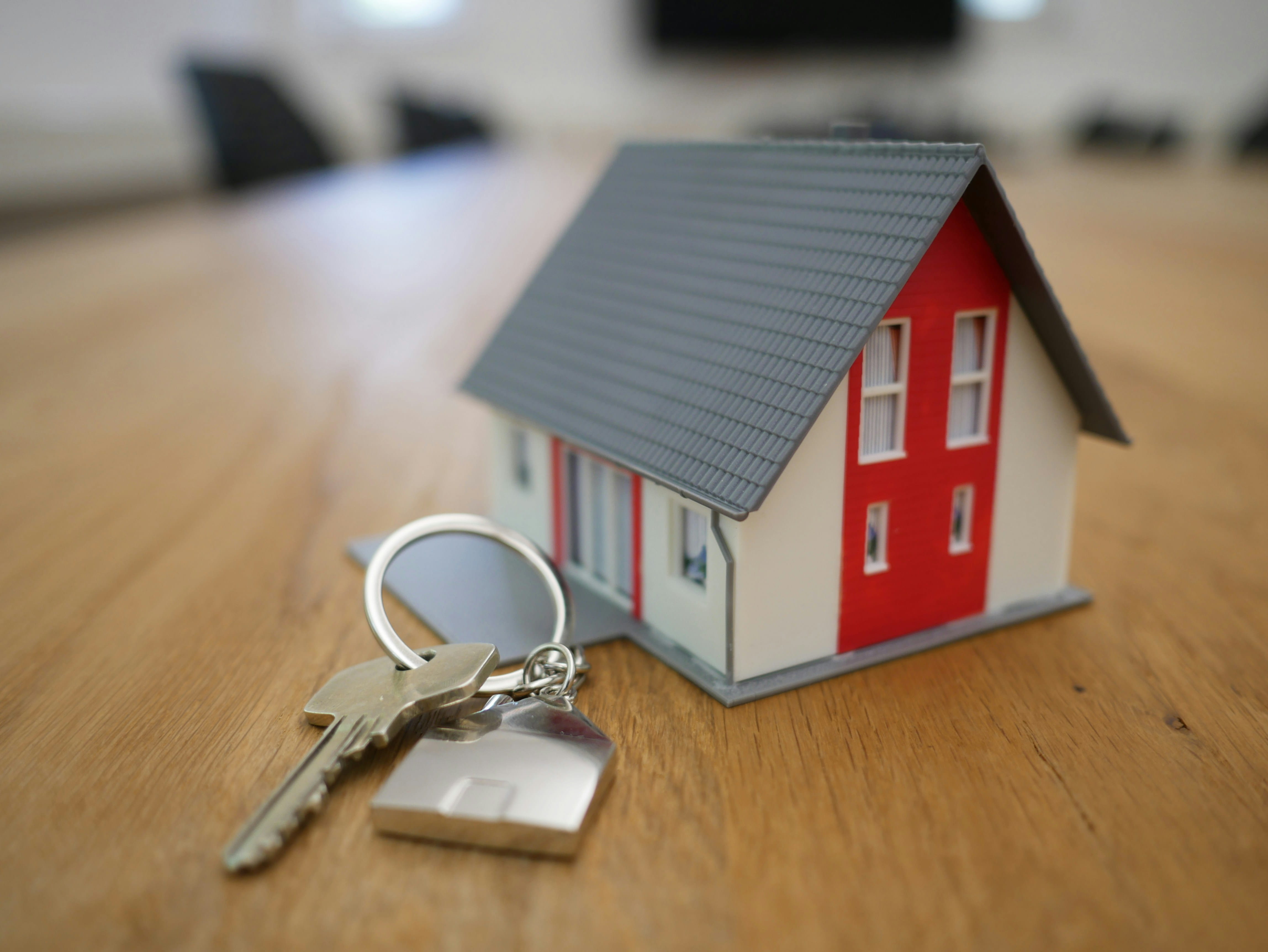 Model of a house on a table with house key next to it