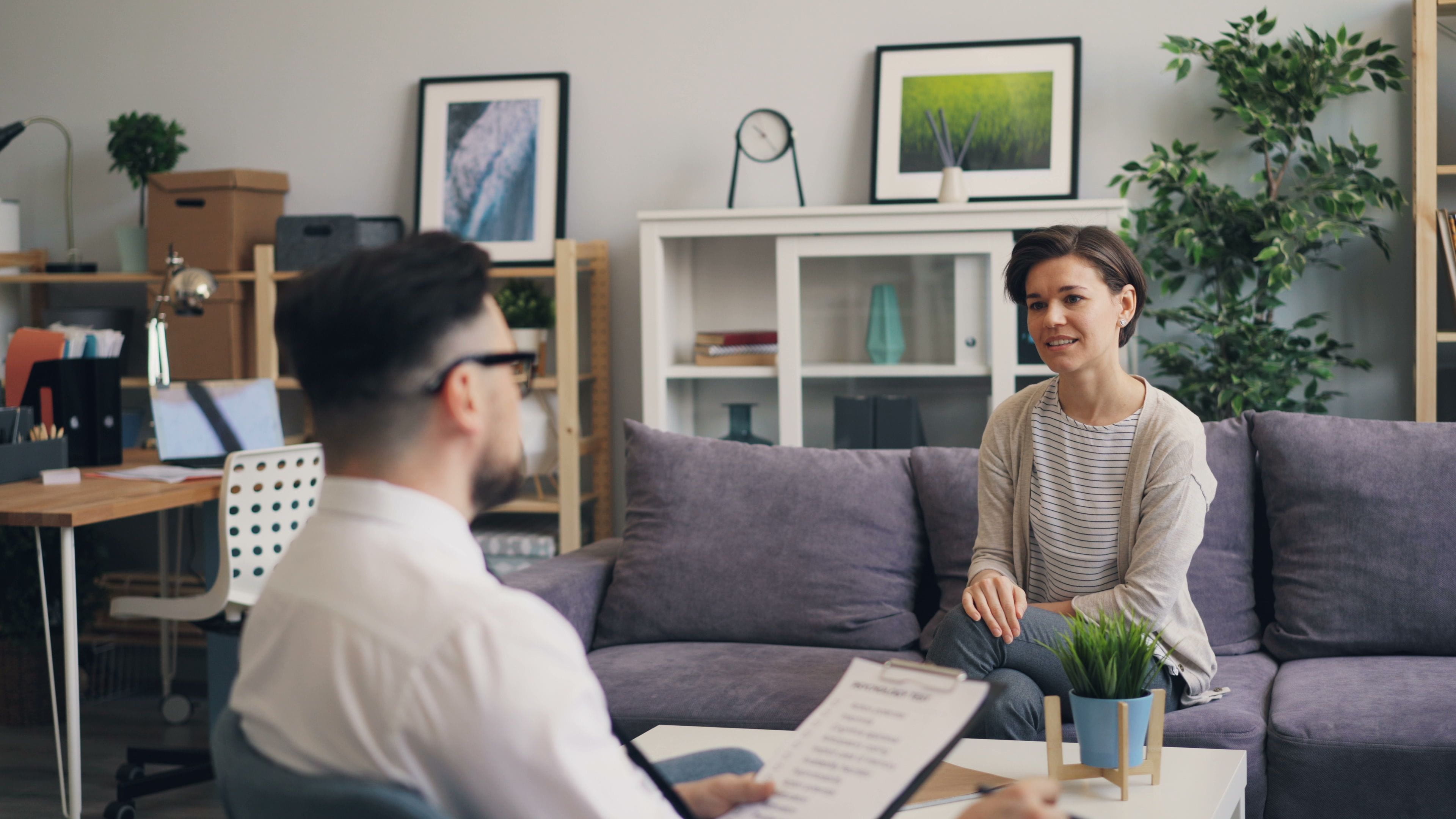 Woman sitting on couch across form Social Worker with a clipboard