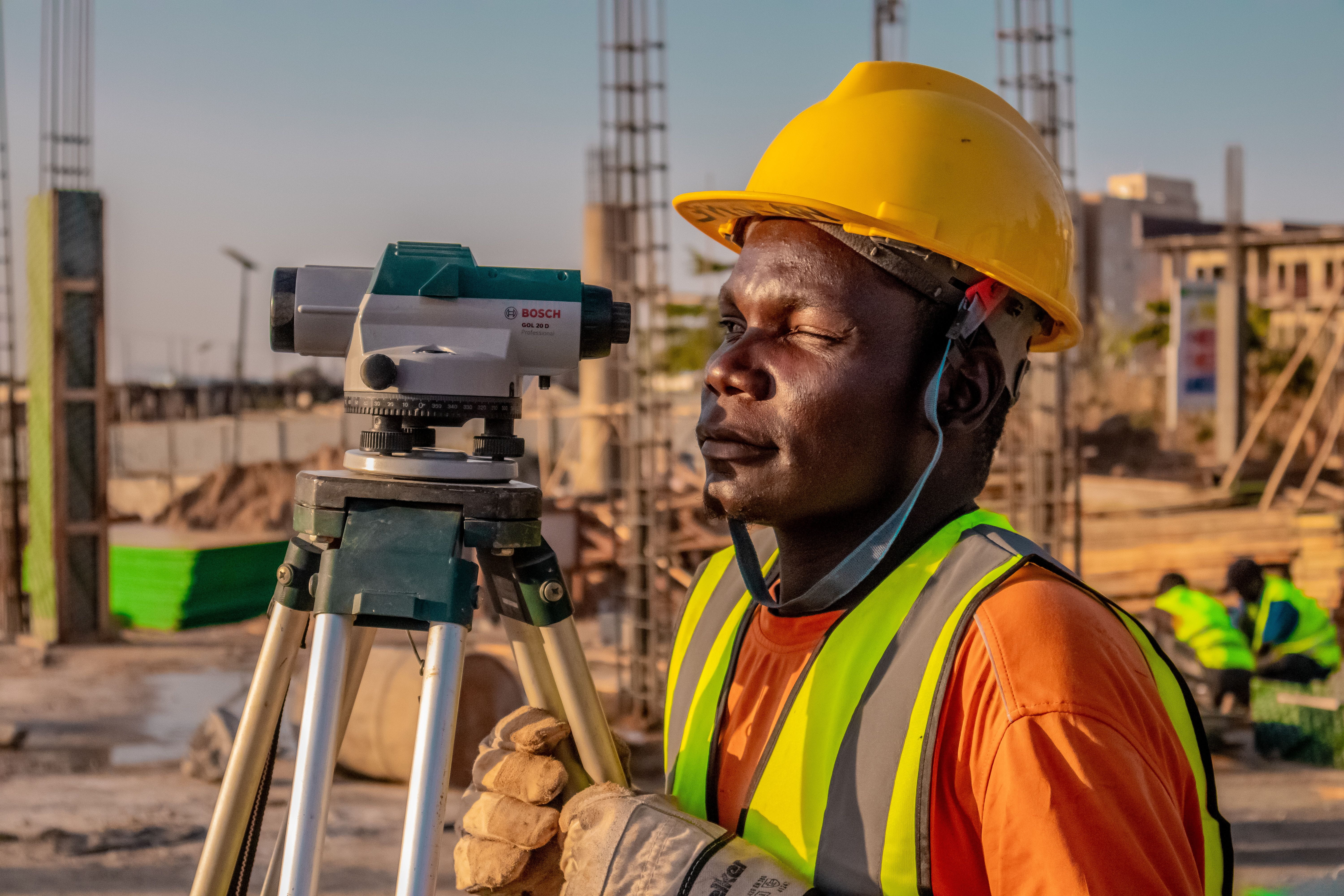 A professional suveyor using a theodolite for land surveying at a building site