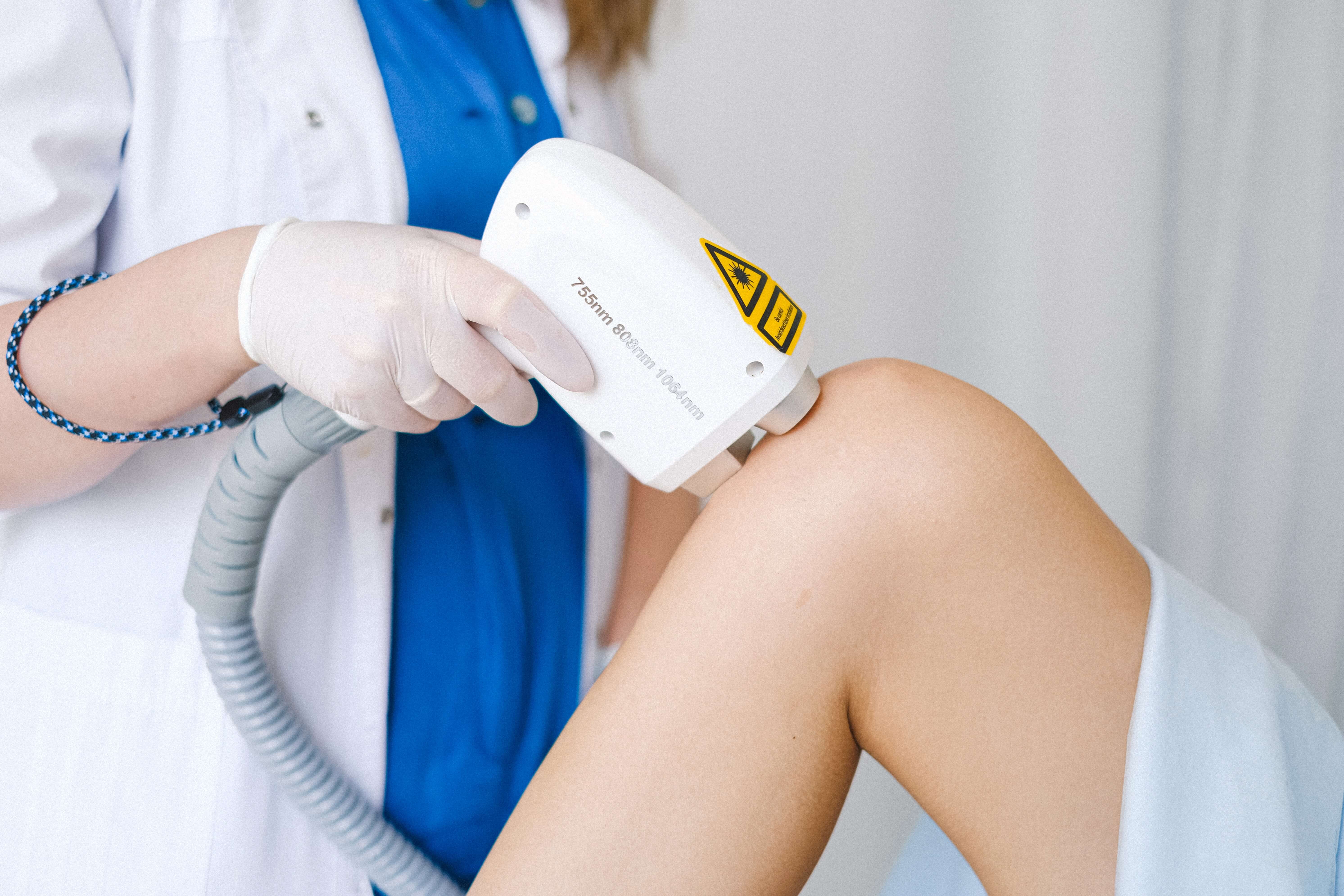 A technician performing a laser procedure on a person's knee