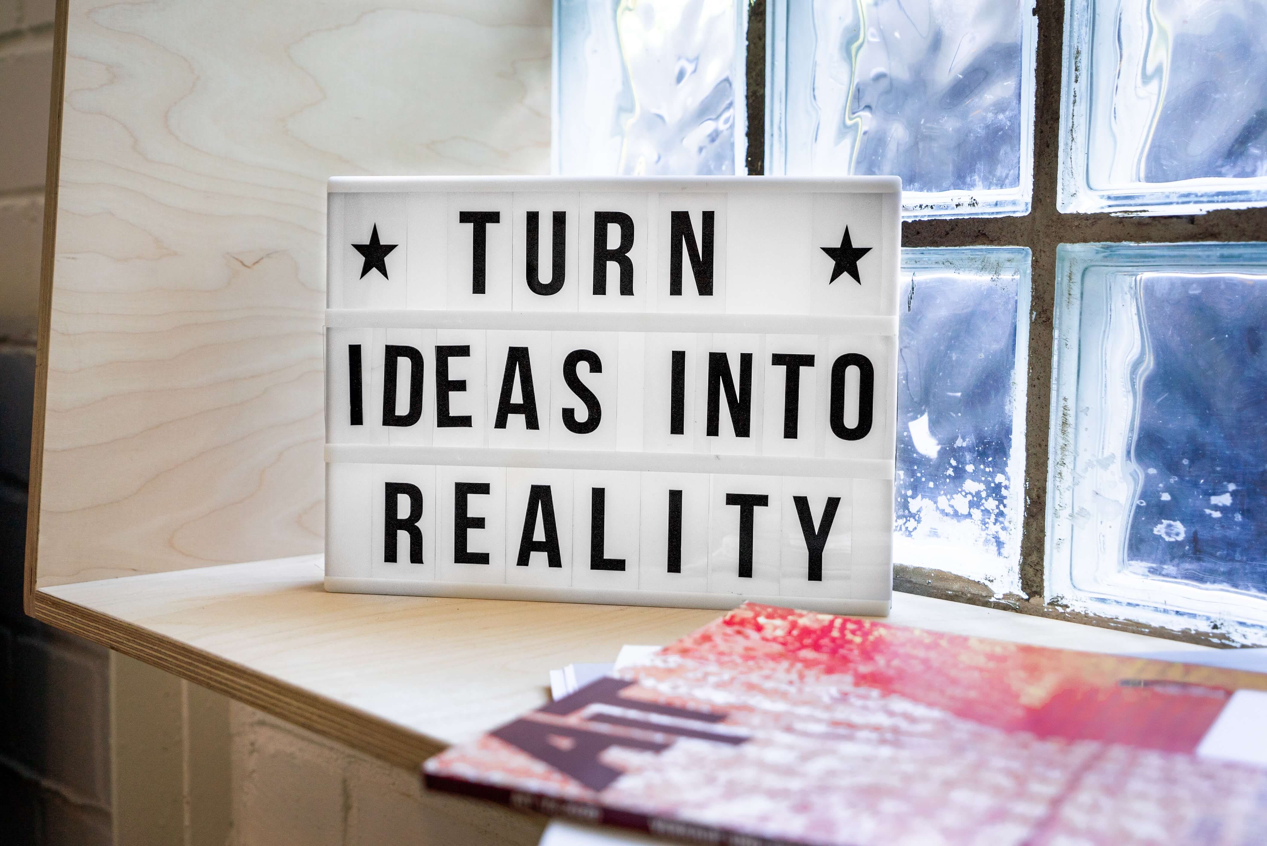 A sign on a windowsill that reads turn ideas into reality.
