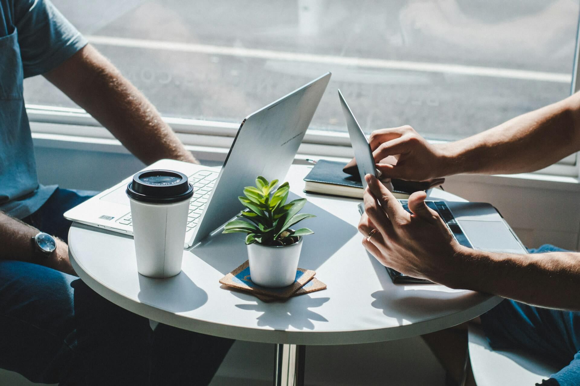 Two people meeting over coffee with their laptops open