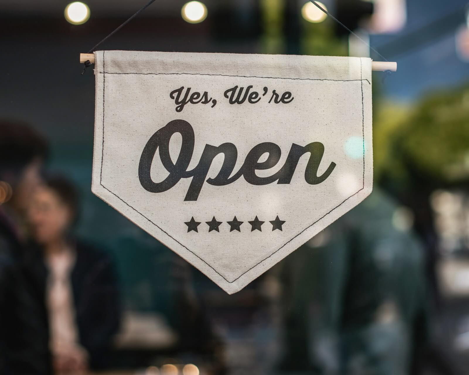 Sign hanging in a window displaying "Yes, we're open"