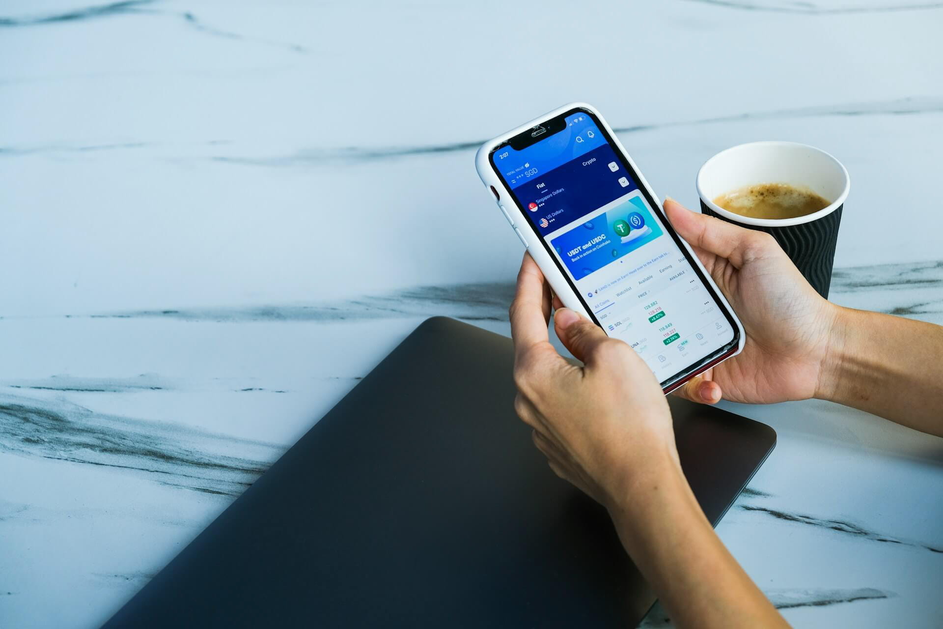 Hands holding a phone displaying a crypto app