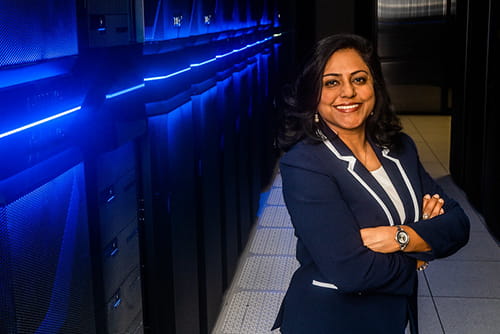 Woman in suit standing in front of row of servers 