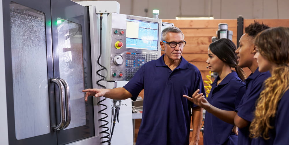 Man explaining machinery to group of apprentices