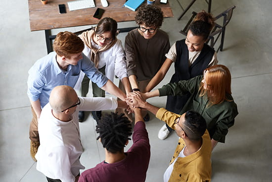  people in circle joining hands in the middle