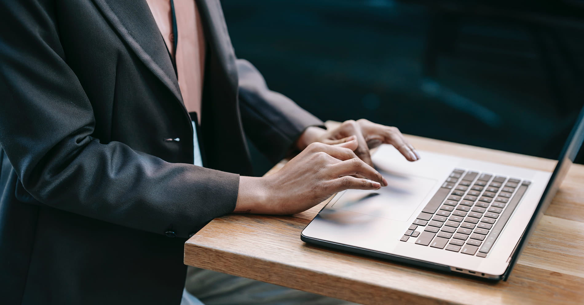 person in blue suit coat and hands on laptop