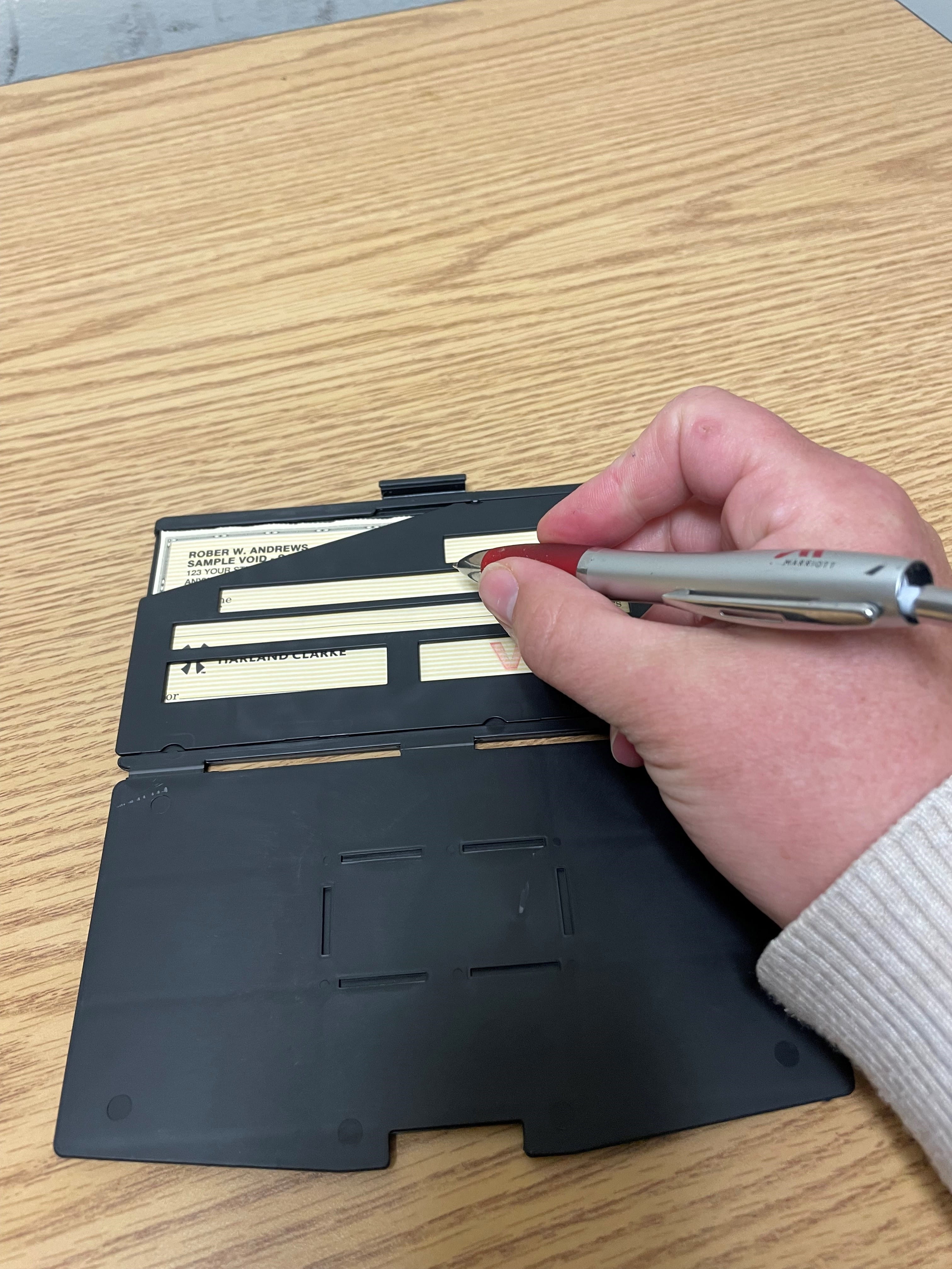 Person signing a check with a check guide