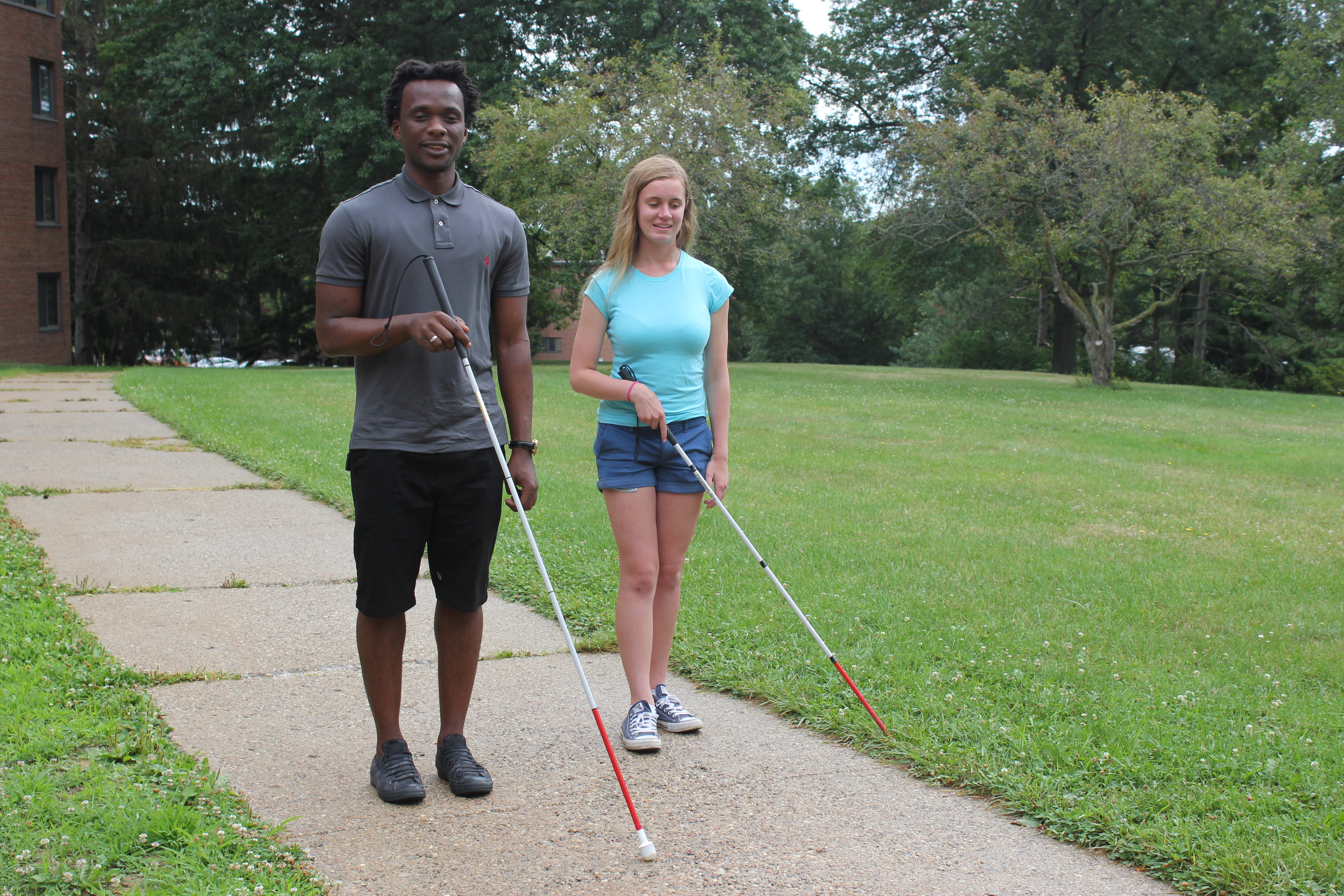 Two students with canes walking on campus.
