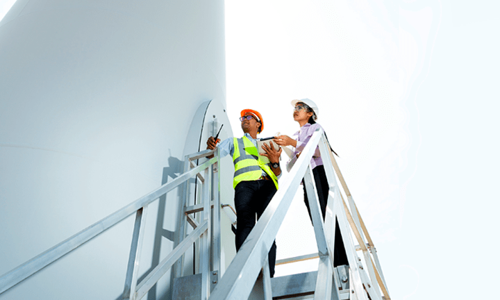 Two workers in construction hats standing on the stairs of windmill