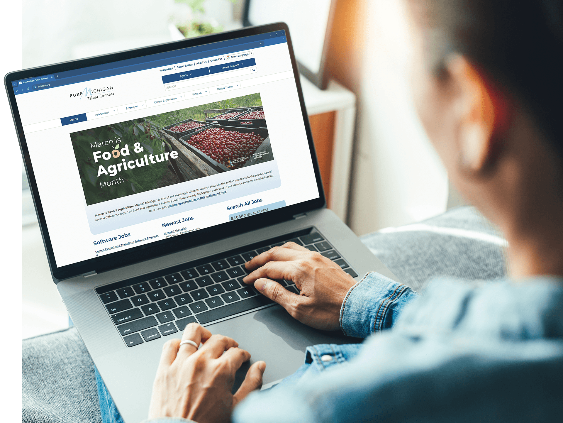 Person using a laptop to view the Pure Michigan Talent Connect website, which displays a banner promoting Food & Agriculture Month and job categories such as software jobs, newest jobs, and all available jobs.