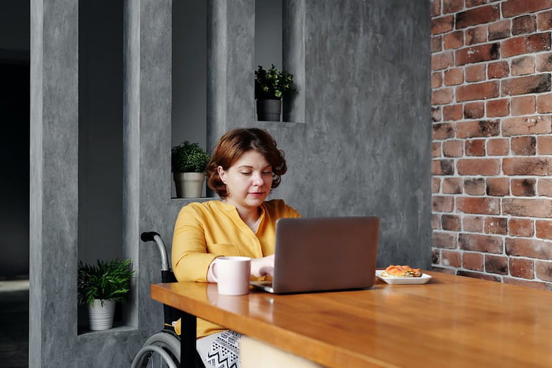 wheelchair bound woman using laptop at table 