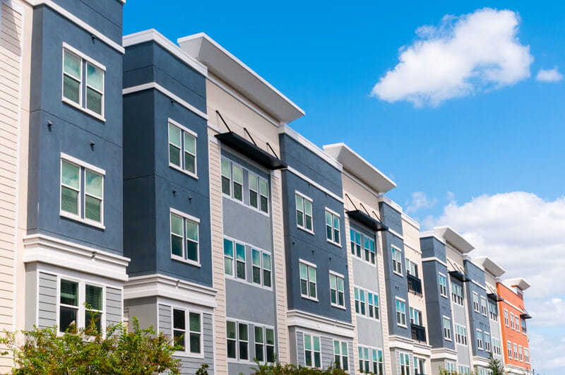 A modern apartment complex with rows of windows and a blue cloudy sky.